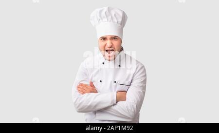 Arrabbiato Chef uomo grida attraversando le mani in piedi in studio, Panorama Foto Stock