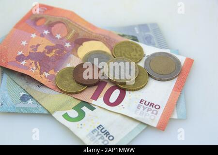 Close-up di 10 e 5 euro le fatture in cui vi sono alcuni cent di euro monete tutte su un tavolo bianco Foto Stock
