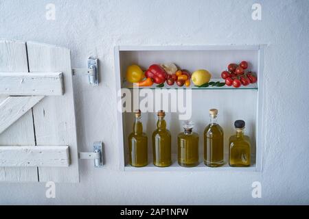 piccola mensola sul muro con bottiglie bottiglia di olio d'oliva e verdure pomodori limone paprika e aglio, vecchio appartamento casa moderna fienile otturatore Foto Stock