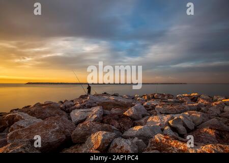 Alba 2020. Pescatore di fronte un breakwave. 2020, Gennaio, 05. Atene, Grecia. Foto Stock