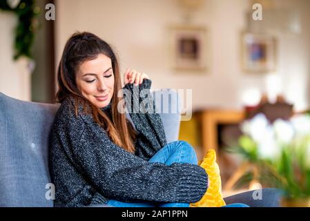 Colpo di attraente donna sorridente seduto in poltrona e fantasticando. Foto Stock