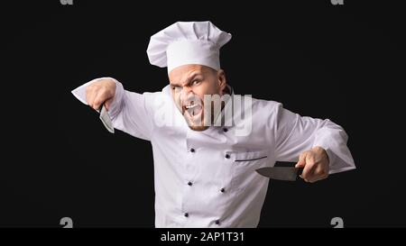 Crazy Chef Uomo con coltelli minacciando in posa di Studio, Panorama Foto Stock