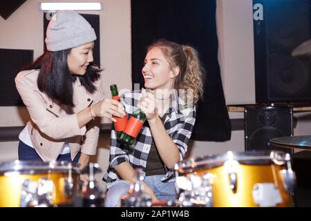 Ritratto di due giovani alla moda donna tintinnio di bottiglie di birra in music studio, shot con flash Foto Stock