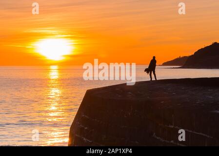 Lyme Regis, Dorset, Regno Unito. Il 20 gennaio 2020. Regno Unito Meteo. Un uomo in piedi sul porto di Cobb parete e guardare il tramonto a Lyme Regis nel Dorset alla fine di una fredda giornata di sole. Credito Foto: Graham Hunt/Alamy Live News Foto Stock