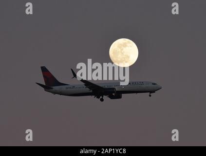 Un aereo Delta Airlines Boeing 737-900ER atterra sotto una luna piena vicino all'aeroporto internazionale di Orlando o MCO. Foto Stock