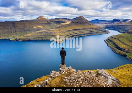 Escursionista gode di vedute di fiordi da una montagna vicino a Funningur su isole Faerøer Foto Stock