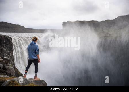 Escursionista in piedi al bordo della cascata Dettifoss in Islanda Foto Stock