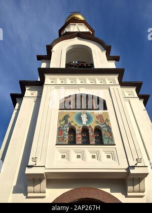 Il campanile della chiesa ortodossa con i volti dei santi sulla facciata, la vista dall'alto contro il cielo blu. Foto Stock