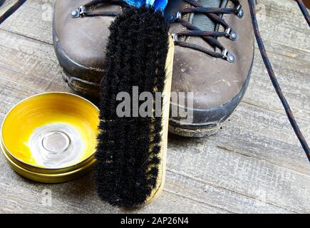 Pulizia sporco marrone stivali in pelle: scarpe, box con scarpa cera, panno blu e nero spazzola sulla tavola di legno Foto Stock