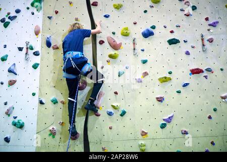 Free climber bambino ragazzo giovane praticare su massi artificiali in palestra, bouldering Foto Stock