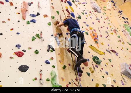 Free climber bambino ragazzo giovane praticare su massi artificiali in palestra, bouldering Foto Stock