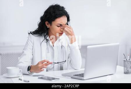 Stanco insegnante messicano massaggiando il naso e gli occhi Foto Stock