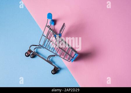 Svuota carrello della spesa sul blu e rosa colore di sfondo. Copia spazio per il testo o il design. Foto Stock