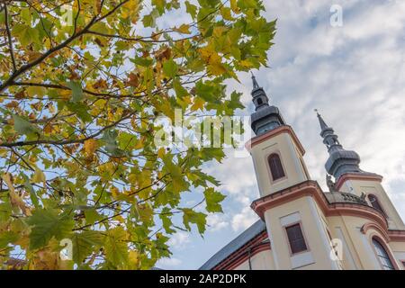 Beautiful scene of tower of castle in Litomysl with autumn leaves in foreground and blue sky with clouds. Foto Stock