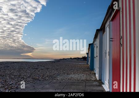 Spettacolare formazione di nubi sul lungomare di Bognor Regis con colorate capanne sulla spiaggia e, bei colori e riflessi del mare. Foto Stock