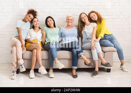 Le donne di diverse età seduti sul divano sorridendo Indoor Foto Stock