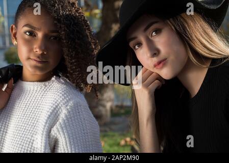 Close up ritratto di due giovani spagnolo fashion girls. Generazione Z. Ragazza in un cappello nero, una ragazza con i capelli ricci. Sorelle. fidanzate ragazze in posa per Foto Stock