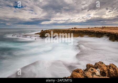 Lunga esposizione cattura delle acque ruvide sulla costa frastagliata dell'Oceano Indiano alla Stazione di Quobba nell'Australia Occidentale. Foto Stock