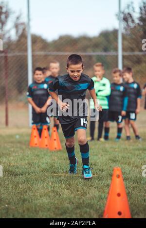 Esercitazioni di calcio: il trapano di slalom. Il calcio giovanile pratica esercitazioni. Giovane calciatore della formazione del passo . Soccer slalom trapano a cono. Ragazzo in soccer jerse Foto Stock