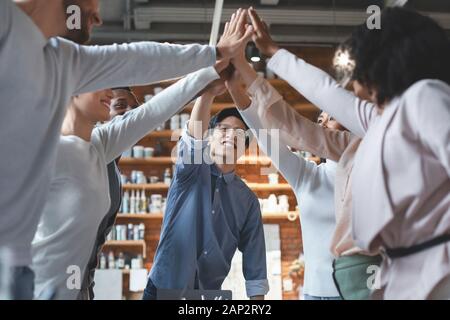 Multirazziale giovane team dando alta cinque in ufficio Foto Stock