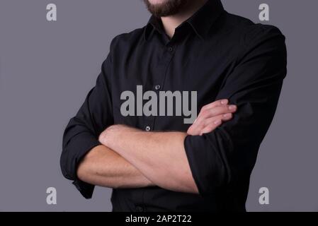 Un uomo in giacca nera, su sfondo grigio scuro. Concetto minimalista. Spazio libero vuoto. Ritratto di un giovane ragazzo in un vestito nero business, tenuta Foto Stock