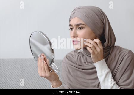 Ragazzina musulmana in Hijab cercando in specchio rotondo e a contatto con la pelle Foto Stock