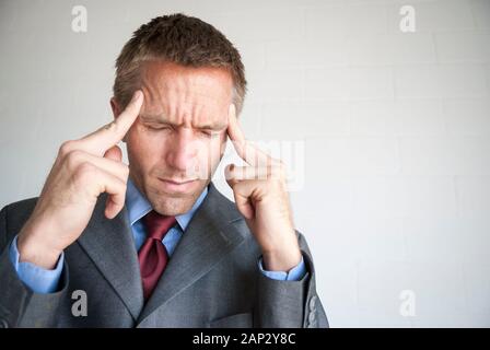 Sottolineato imprenditore strofinando il suo tempio con gli occhi chiusi per alleviare il suo mal di testa Foto Stock