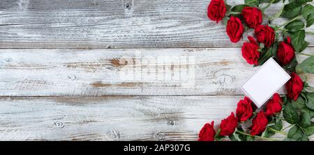 Piccola confezione regalo con una dozzina di rose rosse per il giorno di San Valentino su bianco legno rustico Foto Stock