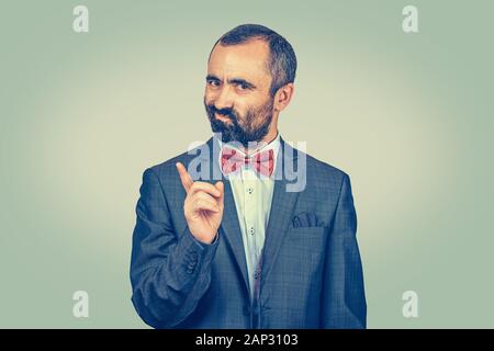 Uomo maturo gesticolando a nessun segno. Ritratto infelice, gravi sono di mezza età guy sollevando il dito indice fino dicendo oh no che non avete fatto che sul verde chiaro yell Foto Stock