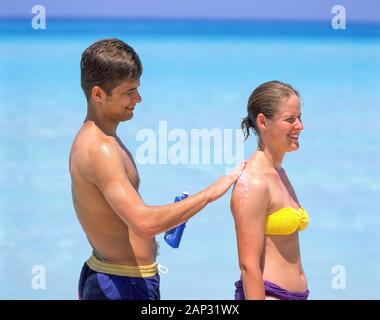 Giovane uomo crema solare di sfregamento sulla donna torna sulla spiaggia tropicale,, Varadero Matanzas, Repubblica di Cuba Foto Stock