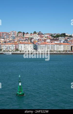 Verde a Dritta boa segnaletica segnando un canale a Santander Spagna con case in riva Foto Stock