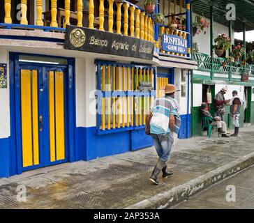 Gli uomini di fronte colorati edifici coloniali (banca, hotel, piccolo negozio) nel triangolo di caffè città del Salento, dipartimento di Quindio, Colombia Foto Stock