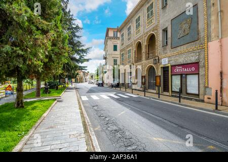 Alberi e piccola linea verde la strada principale attraverso la sezione più recente del villaggio sulla collina di Dolceacqua, Italia, sulla Riviera Italiana. Foto Stock