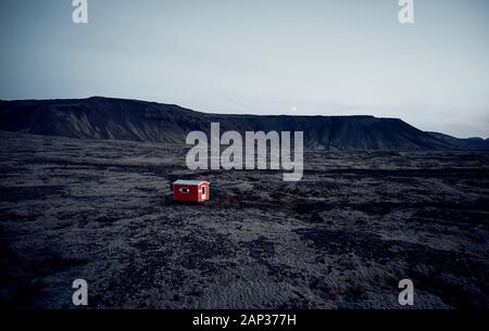 Da sopra luminosa casa rossa con tetto bianco nel deserto secco valle circondata da colline rocciose Foto Stock