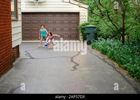 Due bambini piccoli a piedi nudi giocano insieme a basket nel vialetto Foto Stock