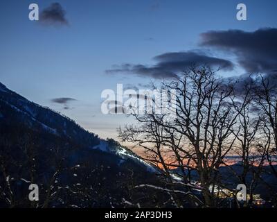 Silhouette di alberi contro il cielo e le montagne di sera sulla Rosa Khutor dall'hotel balcony Foto Stock