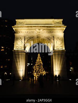 Vista frontale del Washington Square Arch nel Washington Park con un albero di Natale sotto illuminato di notte a Manhattan, New York, NY Foto Stock