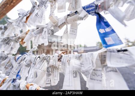 Saga, Giappone - nov. 12, 2018: giapponese random fortune raccontando carta (Omikuji) ripiegato e legato sulla corda fili (Omikuji kake) nel tempio tradizionale, conce Foto Stock