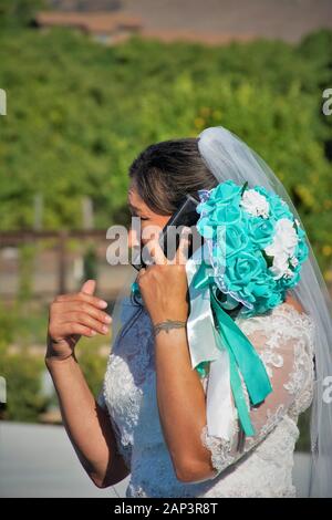 Donna al matrimonio sposa parlare su cellulare con persone che non sono arrivati a cowboy riunione etnica nel sud della California Foto Stock