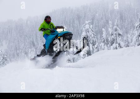 Uomo avventuroso in sella ad una motoslitta nel bianco della neve Foto Stock