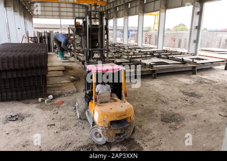 Lavoratore cavalcare carrello in alimentazione di costruzione,l'asta in acciaio e calcestruzzo, foglio di fabbrica. Foto Stock