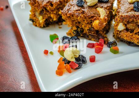 Primo piano di frutta secca con le fette di torta di prugne sullo sfondo. Foto Stock