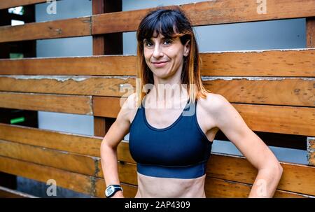 Atleta femminile allegro di fronte a uno sfondo di legno Foto Stock