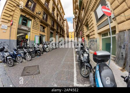 а strada pavimentata tipica del centro di Napoli piena di moto parcheggiate in una linea. Foto Stock