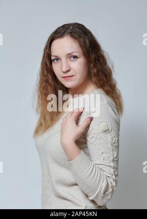 Giovane donna in posa davanti alla telecamera con capelli ricci Foto Stock