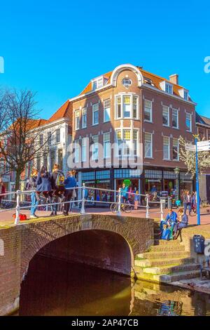 Delft, Paesi Bassi - 8 aprile 2016: Colorata vista sulla strada con case tradizionali olandesi, ponte, gente e canale Foto Stock