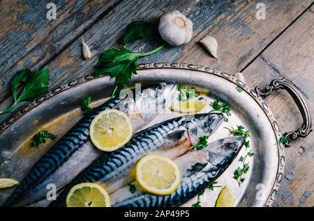 Pesce sgombro fresco con limone e spezie servito su piatto d'argento dall'alto. Piatti di pesce fatti in casa cucina ricetta. Alimenti sani per la dieta preparati per il pranzo Foto Stock