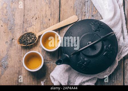 Tradizionale ricetta giapponese di tè alle erbe preparato in ghisa teapot con erbe secche organiche dall'alto. Vista dall'alto della tradizionale bevanda calda asiatica on w Foto Stock