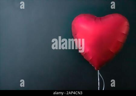 Palloncini d'aria rossi a forma di cuore su sfondo nero. San Valentino, amore. Foto Stock