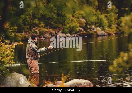 Bobina di corda da pesca del mosca, mano dell'uomo che tiene la canna Foto Stock